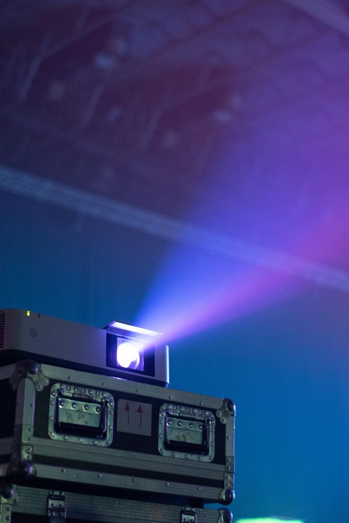 about-us Vibrant light beam projecting from a stacked projector case in a dark room.