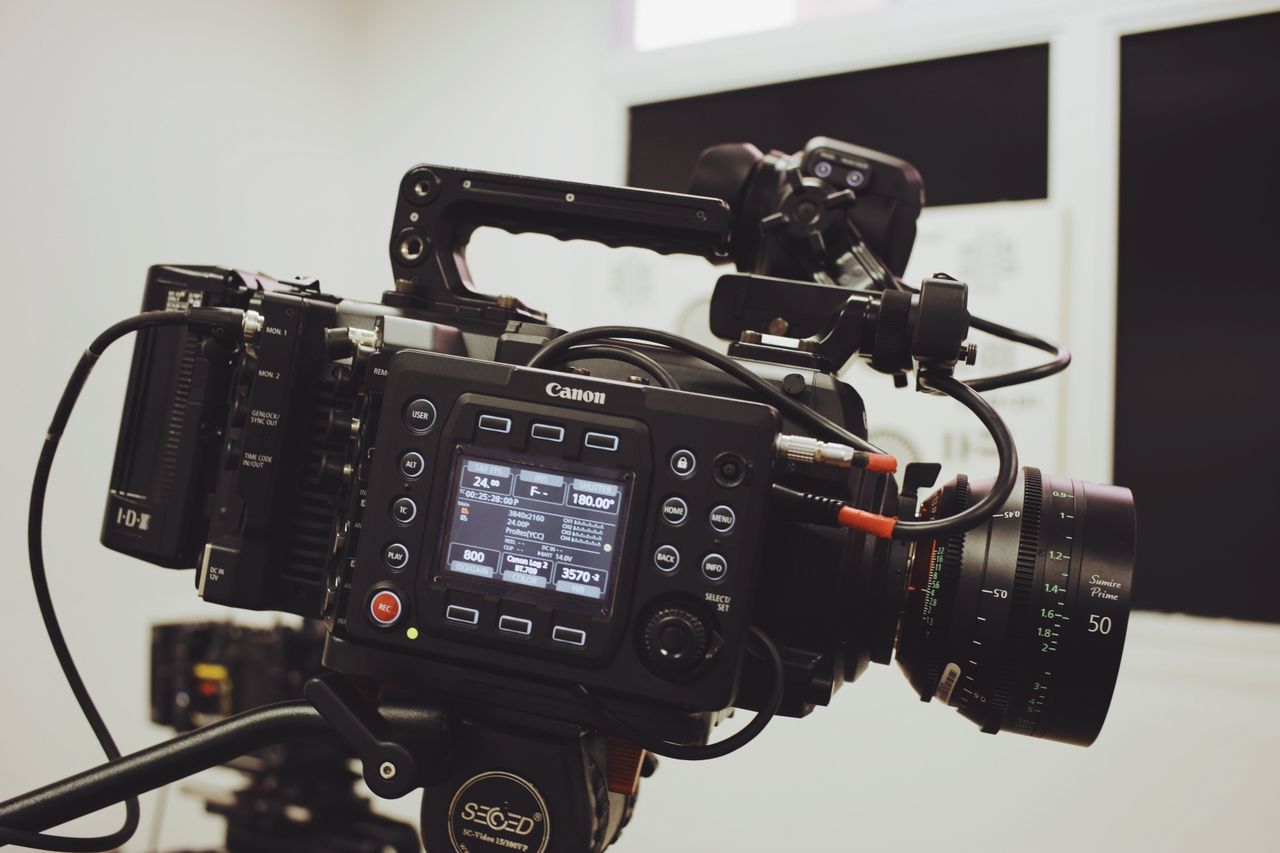 Close-up of a professional video camera setup on a tripod, ready for filming in a studio environment.